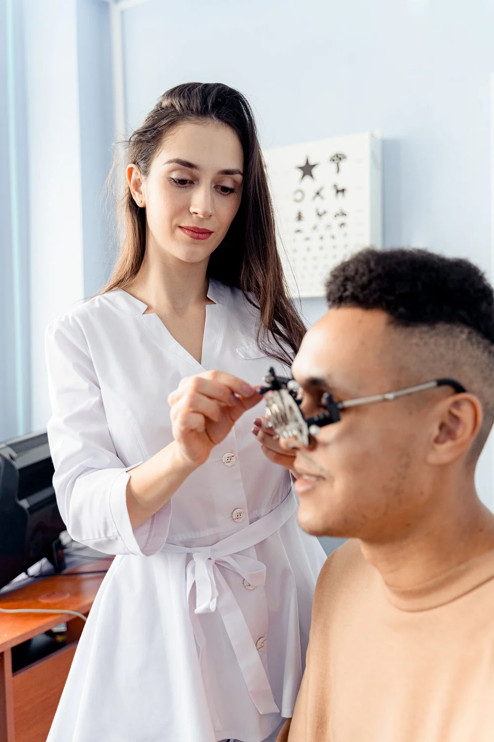 Profissional ajustando uma armação de teste em um homem durante avaliação visual